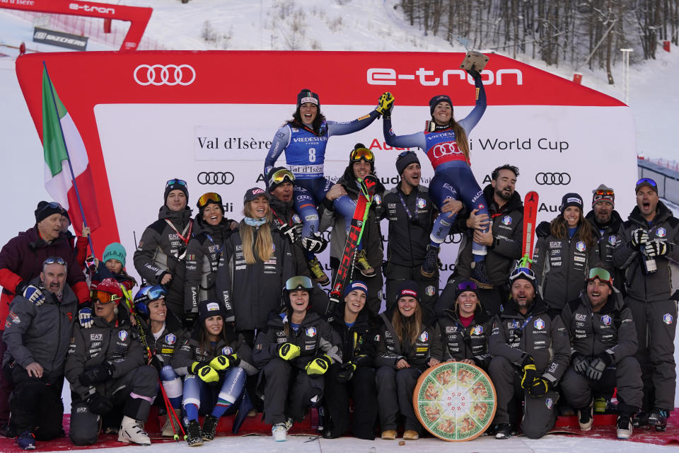 The winner Italy's Federica Brignone and third placed Italy's Sofia Goggia celebrate with the team after an alpine ski, women's World Cup Super G race, in Val d'Isere, France, Sunday, Dec. 17, 2023. (AP Photo/Giovanni Auletta)