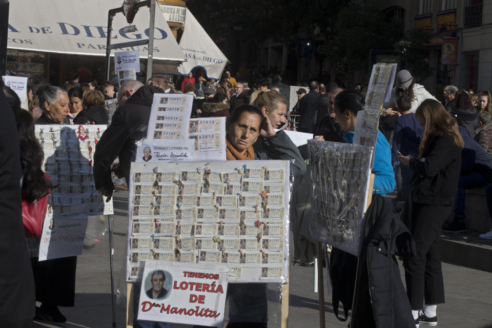 A lottery seller carries a board with Christmas lottery tickets for sale in Madrid, Spain, Saturday, Dec. 7, 2019. The traditional Spanish Christmas lottery draw, known as El Gordo (The Fat One) will take place on Dec. 22. (AP Photo/Paul White)