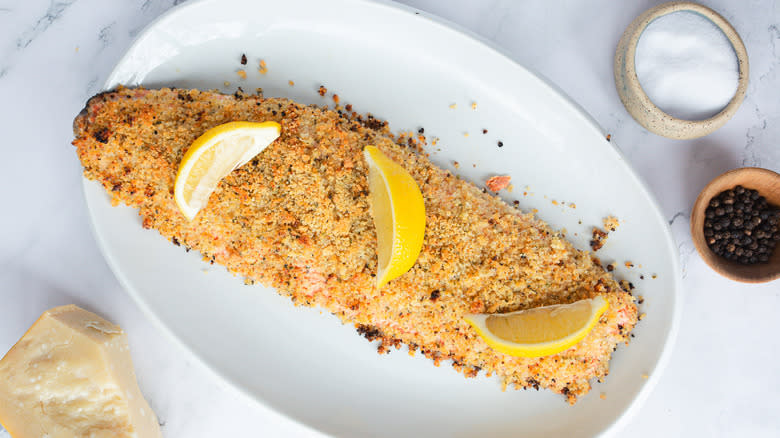 breadcrumb crusted salmon on white platter with lemons