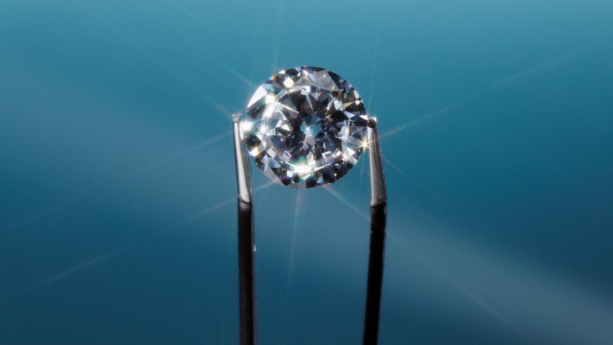  A pair of tweezers holding a diamond. 