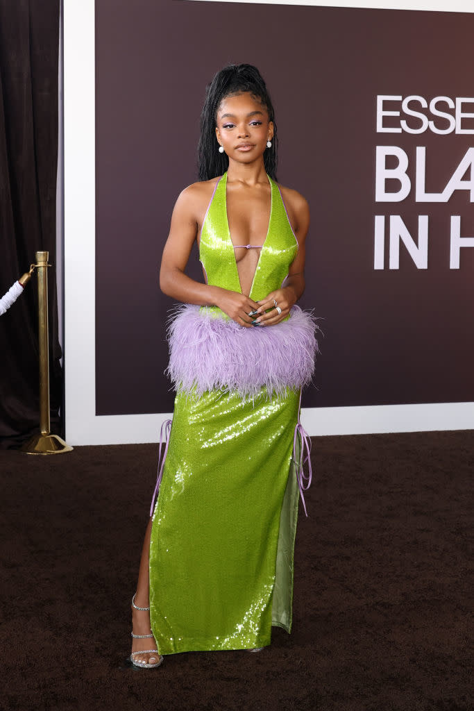 Marsai in glittery halter dress with feather accents at the waist and strappy heels