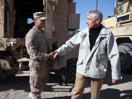U.S. Secretary of Defense Chuck Hagel (R) speaks with U.S. Marine Lance Corporal Arron Corona as he works on a MRAP vehicle during a visit to Camp Bastion, Helmand province December 8, 2013. REUTERS/Mark Wilson/Pool