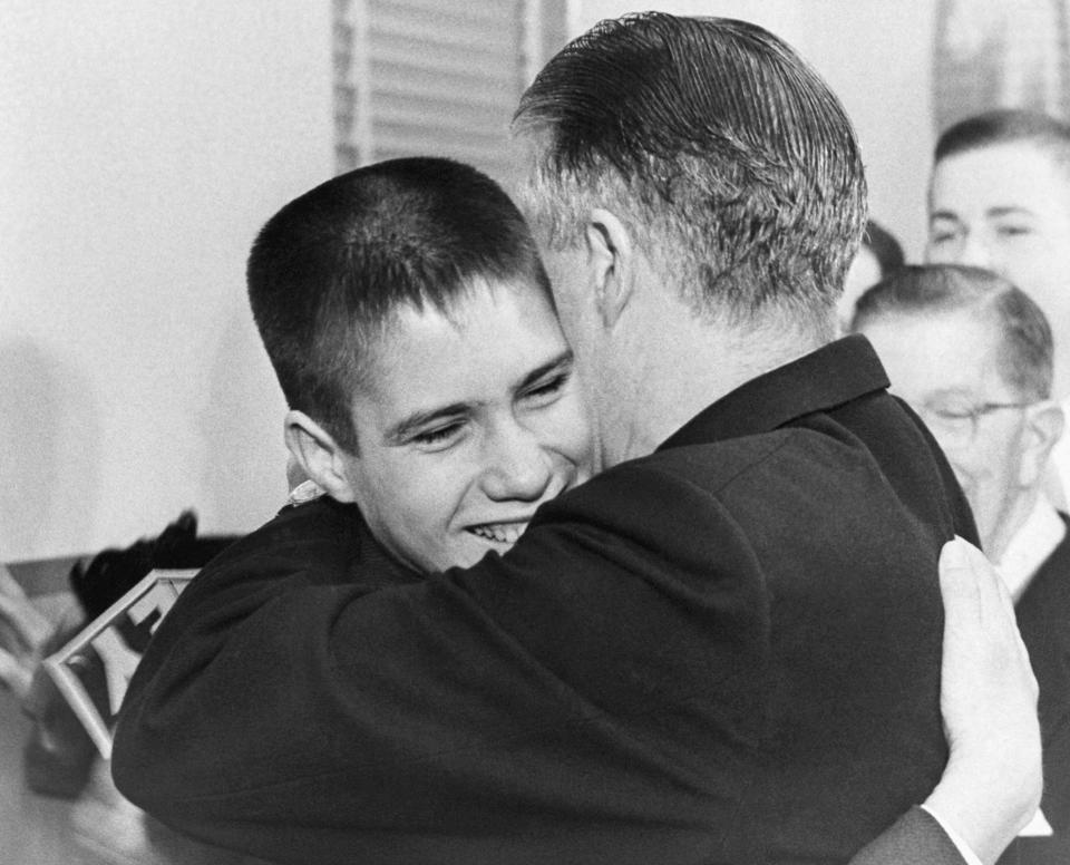 FILE - Mitt Romney, 14, hugs his father George Romney at a Detroit News conference Feb. 10, 1962, after the industrialist announced he would be a candidate for the GOP nomination for governor of Michigan. (AP Photo, File)