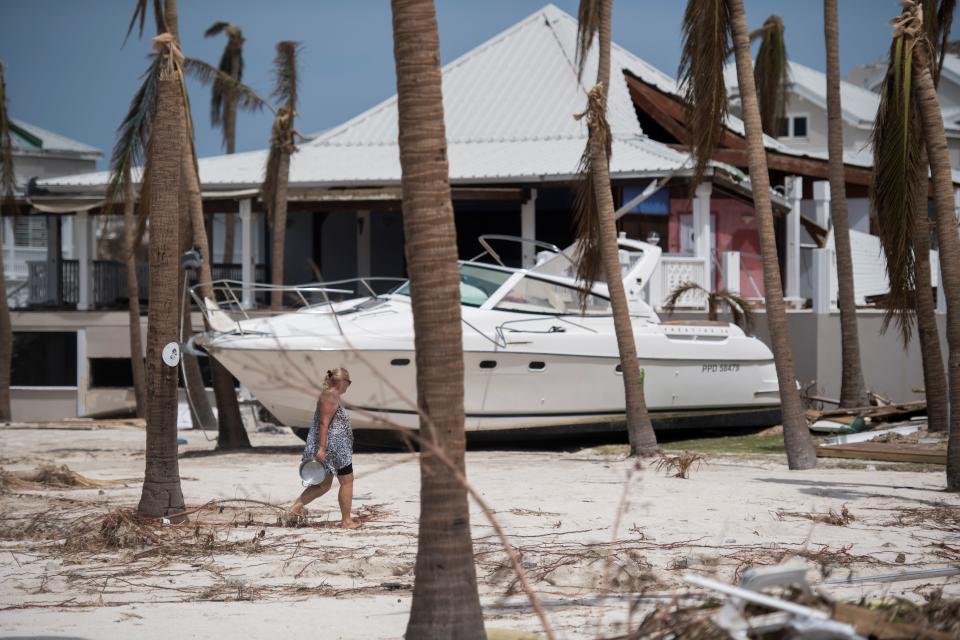 A pedestrian walks past a beached speedboat as it lies among debris in the Baie Nettle area of Marigot on Saint Martin island on September 12, 2017, after it was devastated by Hurricane Irma.