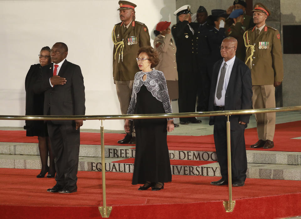 President Cyril Ramaphosa, front left, and his wife, Tshepo Motsepe, centre, stand to attention for the national salute at the opening of the sixth parliament in Cape Town, South Africa, Thursday, June 20, 2019. (Kim Ludbrook/Pool Photo via AP)