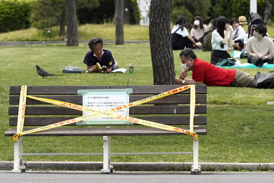 FILE - In this May 14, 2020, file photo, people rest on the grasses at a park in Yokohama, Kanagawa prefecture, near Tokyo. As Japanese return to schools, shops and offices reconfigured to help prevent new coronavirus infections with ample use of plastic screens, masks and reminders to keep their distance, access to faster testing is crucial, officials say.(AP Photo/Shuji Kajiyama, File)