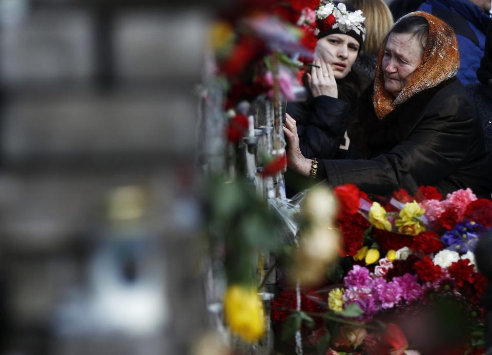 People mourn at the site where anti-Yanukovich protesters have been killed in recent clashes in Kiev