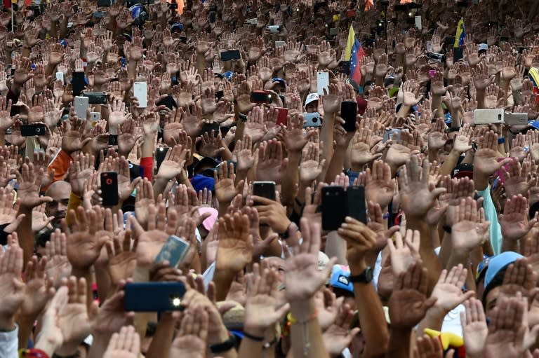 People raise their hands during a mass opposition rally against President Nicolas Maduro on January 23, 2019, after National Assembly head Juan Guaido declared himself the country's 'acting president'