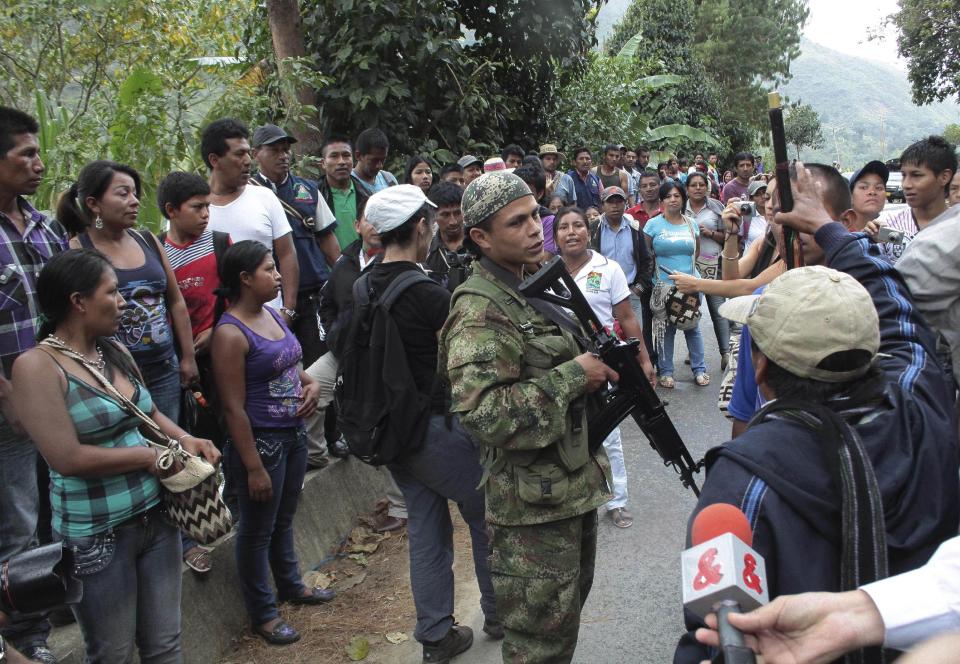 Indians surround a rebel of the Revolutionary Armed Forces of Colombia, FARC, on the outskirts of Toribio, southern Colombia, Wednesday, July 11, 2012. Rebels set up a roadblock on a road leading to Toribio while Colombia's President Juan Manuel Santos was holding a meeting with cabinet members and local authorities in the church of the town, that was attacked by guerrillas last week. (AP Photo/Juan Bautista Diaz)