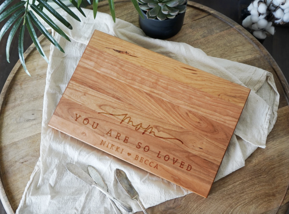 Personalized Mother's Day Charcuterie Board wooden board with writing engraved on it (Photo via Etsy)