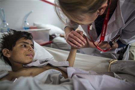 Gullali, 10, who sustained bullets injuries, is comforted by nurse Nicole Burwood at Emergency hospital in Kabul March 27, 2014. REUTERS/Zohra Bensemra