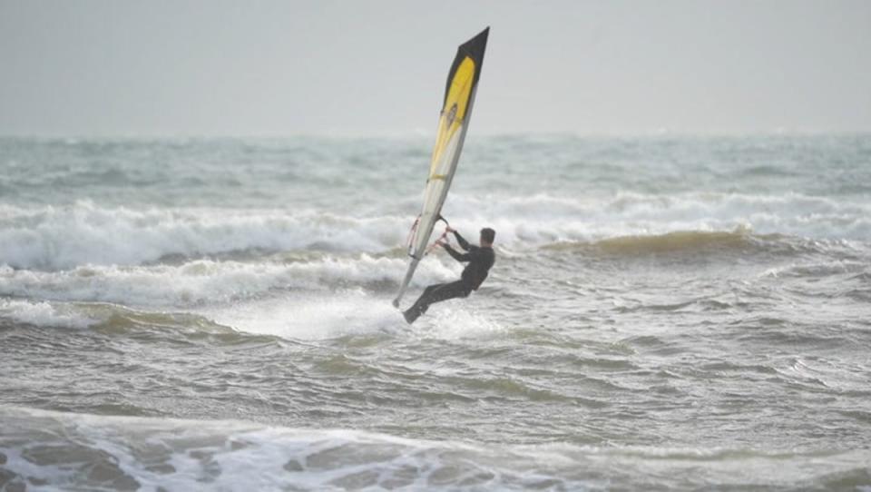 People kite and windsurf on Avon Beach as windy weather hits UK. (PA)