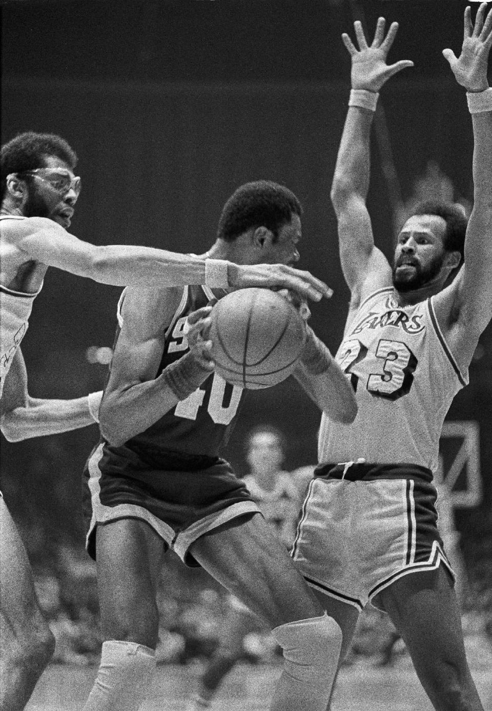 FILE - In this April 15, 1978 file photo, Los Angeles Lakers' Kareem Abdul-Jabbar, left, reaches for the ball held by Seattle Supersonics Marvin Webster, center, as Lakers' Lou Hudson (23), right, defends during an NBA playoff game in Los Angeles. Six-time All-Star Lou Hudson died Friday, April 11, 2014, in Atlanta, the Atlanta Hawks said. He was 69. (AP Photo/File)