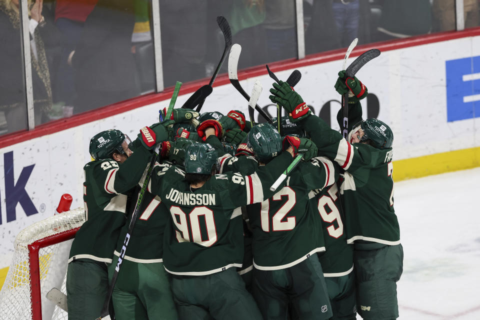 Minnesota Wild players surround goaltender Marc-Andre Fleury in celebration after winning against the New York Islanders following an NHL hockey game, Monday, Jan. 15, 2024, in St. Paul, Minn. (AP Photo/Stacy Bengs)