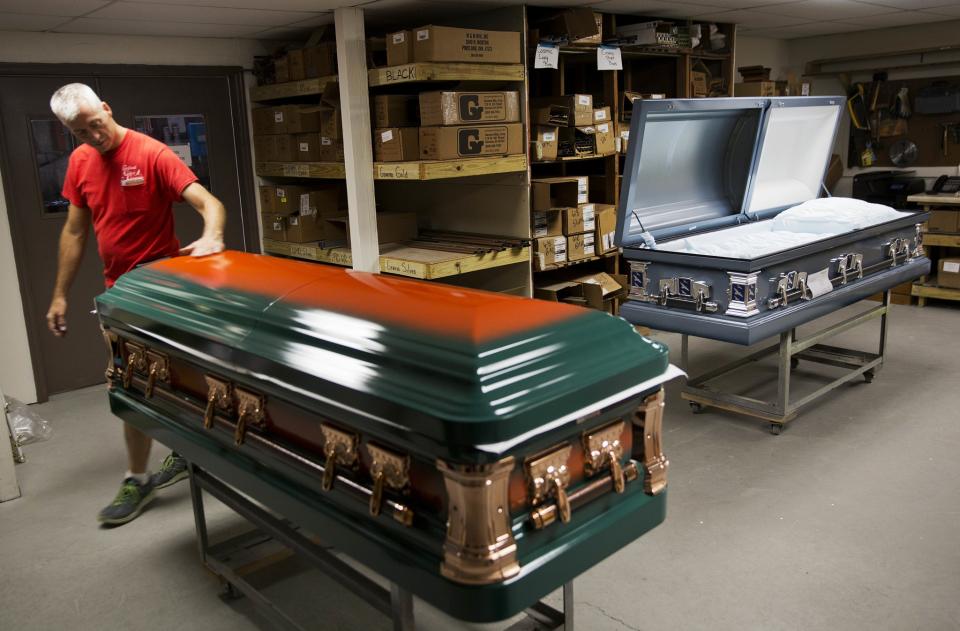 <p>Kelly Greenwood, co-owner of Cardinal Casket Company, inspects a casket painted in the colors of the University of Miami for a victim of the Pulse nightclub shooting who was also a fan of the university in Orlando. “It hits you, it hits everyone here,” said Greenwood, who lost a friend in the shooting. “I feel proud knowing that I made something for my friend’s mother that will be with them the last time their family sees him.” The locally owned company has so far received 23 orders for caskets before the funerals for the victims. <em>(Photo: David Goldman/AP)</em> </p>