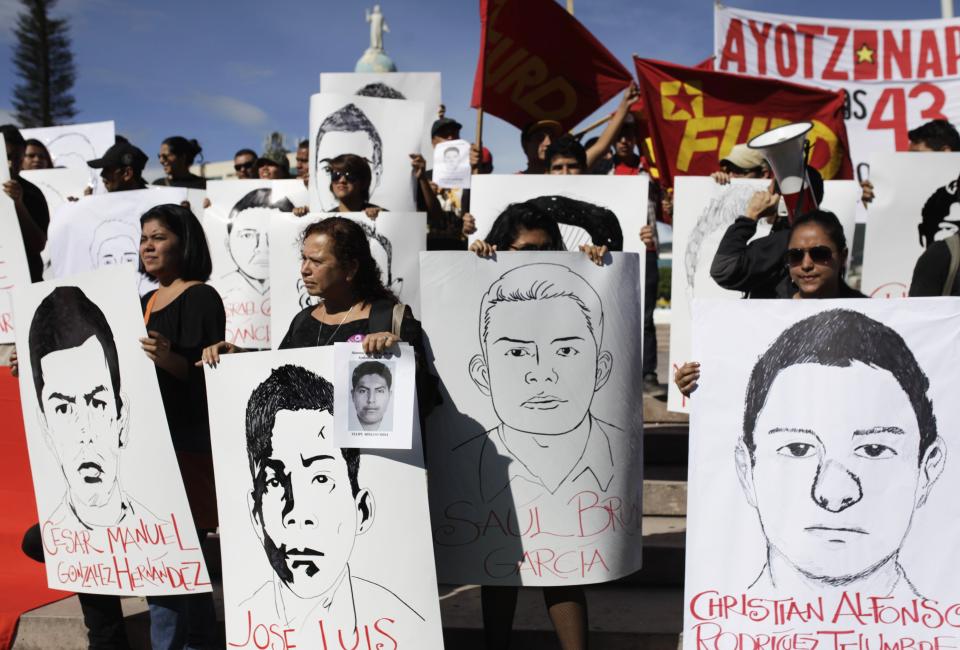 Demonstrators hold sketches and a photograph of missing Ayotzinapa students during a protest in San Salvador