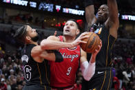 Miami Heat forward Caleb Martin, left, and center Bam Adebayo, right, guard Chicago Bulls center Nikola Vucevic during the first half of an NBA basketball game in Chicago, Saturday, Nov. 27, 2021. (AP Photo/Nam Y. Huh)