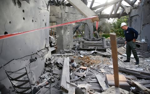 A police officer inspects the damage to a house hit by a rocket in Mishmeret, central Israel - Credit: AP