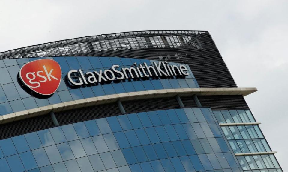 The imposing curved glass facade of GSK's modern headquarters, with its red logo and name prominent at the top of the building