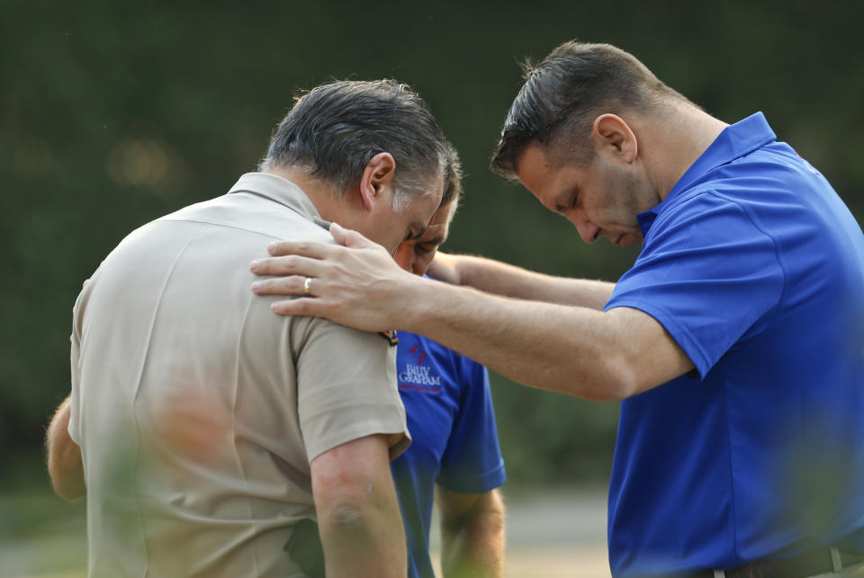 Ventura County Sheriff's Office Capt. Garo Kuredjian, left, embraces chaplains with the Billy Graham Rapid Response Team (RRT) as they pray near the site of Wednesday's mass shooting in Thousand Oaks, Calif., Friday Nov. 9, 2018. Investigators continue to work to figure out why an ex-Marine opened fire Wednesday evening inside a Southern California country music bar, killing multiple people. (AP Photo/Damian Dovarganes)