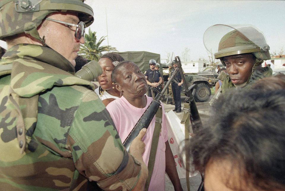 <p>Florida National Guardsman Sgt. Jim Urbanik of Tampa holds out his gun to keep people in line as they wait for food at a distribution center in Florida City, Fla., Aug. 27, 1992. Many residents of this south Dade County farming community lost their homes when Hurricane Andrew came through last Monday. (AP Photo/Lynne Sladky) </p>