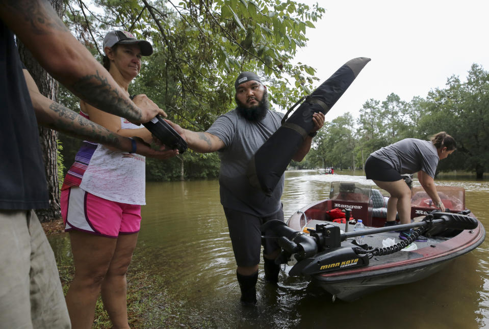 Pete Muniz, center, unloads his firearms off a boat after retrieving them from his flooded home in the Lochshire neighborhood Friday, Sept. 20, 2019, in Huffman, Texas. Emergency workers used boats Friday to rescue about 60 residents of a Houston-area community still trapped in their homes by floodwaters following one of the wettest tropical cyclones in U.S. history. (Godofredo A. Vásquez/Houston Chronicle via AP)