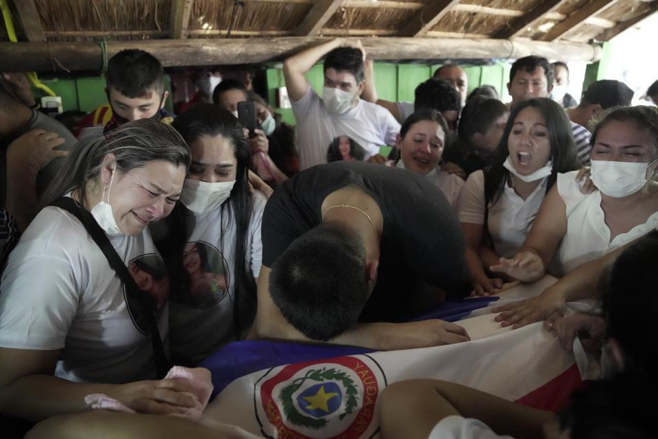 Relatives of Leidy Vanessa Luna Villalba mourn over the flag-draped coffin that contain her remains in her hometown of Eugenio Garay, Paraguay, Tuesday, July 13, 2021. Luna Villalba, a nanny employed by the sister of Paraguay's first lady Silvana Lopez Moreira, was among those who died in the Champlain Towers South condominium collapse in Surfside, Florida on June 24. (AP Photo/Jorge Saenz)