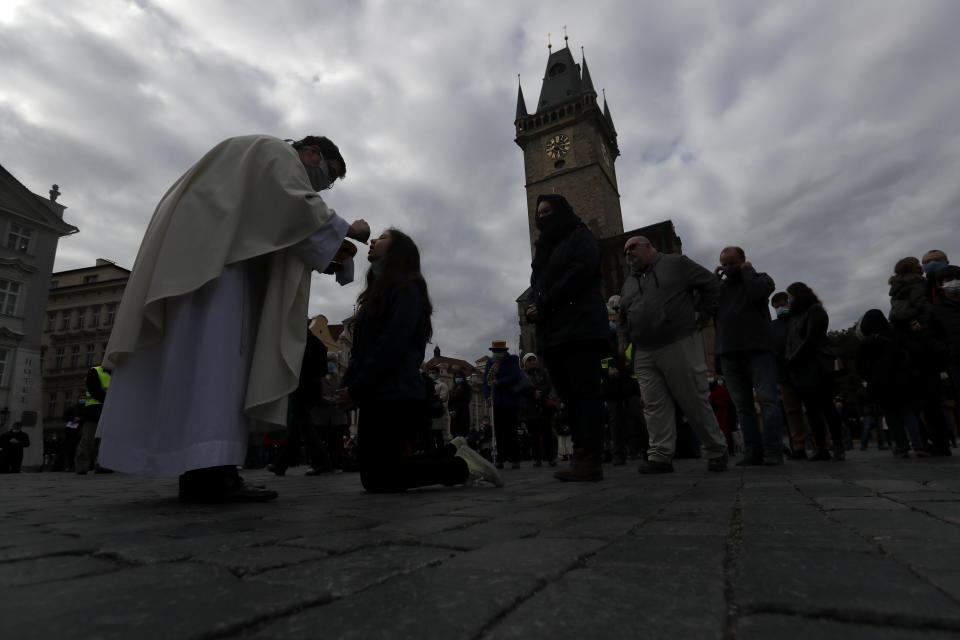 Dozens of worshippers attend a mass celebrated at Old Town Square in Prague, Czech Republic, Sunday, Oct. 18, 2020. As Czech Republic battles new spike of coronavirus infections newly adopted COVID-19 restrictive measures limit indoor gatherings to six people or less. (AP Photo/Petr David Josek)