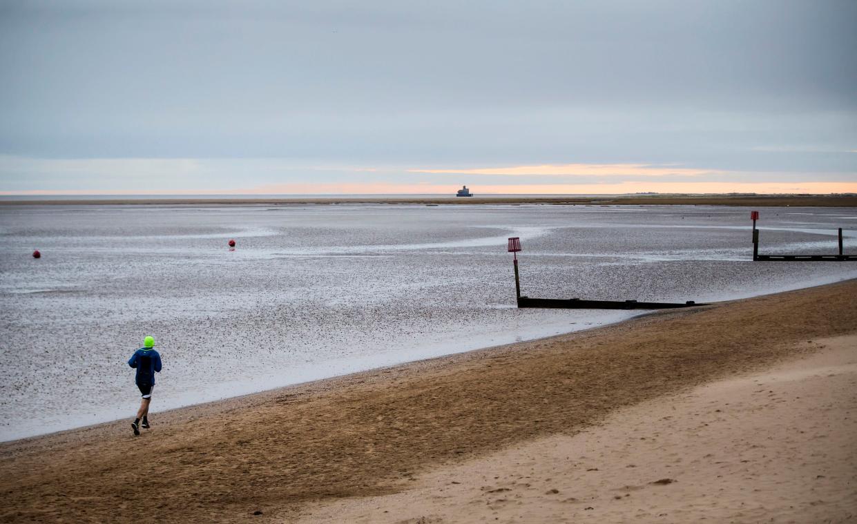 A man jogs in early morning light on the beach at Cleethorpes in North East Lincolnshire.