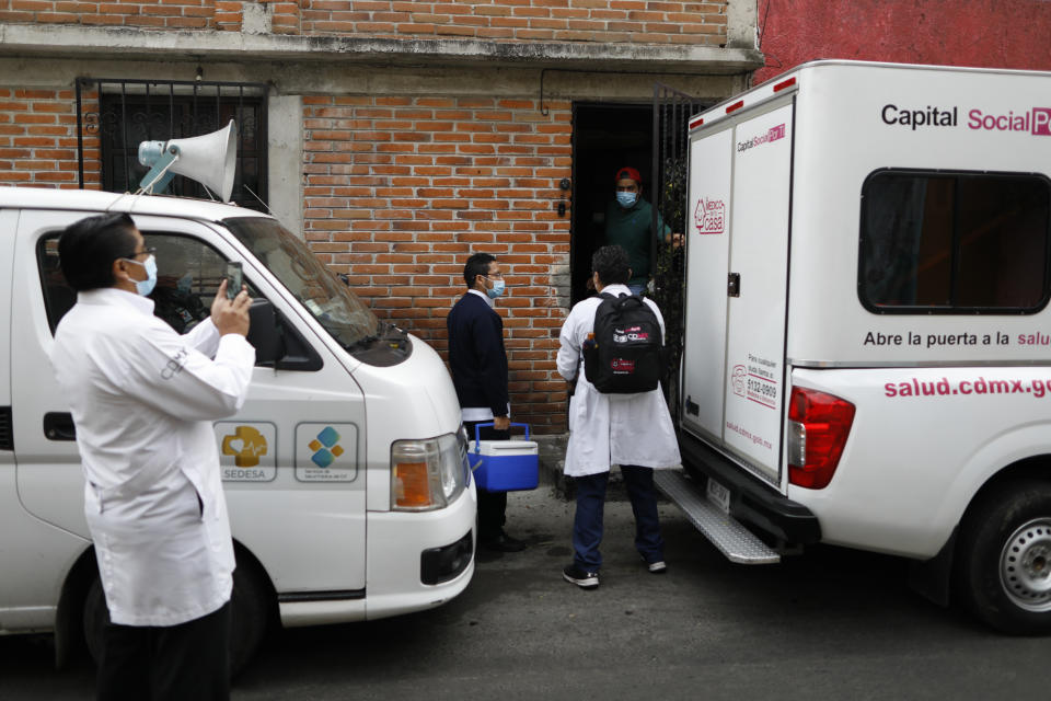 A member of the Moreno family opens the door to welcome a medical team arriving to home test seven members of the family for COVID-19, in the Xochimilco borough of Mexico City, Thursday, Sept. 24, 2020.(AP Photo/Rebecca Blackwell)