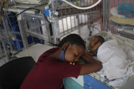 A woman rests close to her newborn son at the Saint Damien Pediatric Hospital of Port-au-Prince, Haiti, Sunday, Oct. 24, 2021. Haiti's capital has been brought to the brink of exhaustion by fuel shortages and the capital's main pediatrics hospital says it has only three days of fuel left to run ventilators and medical equipment. (AP Photo/Matias Delacroix)