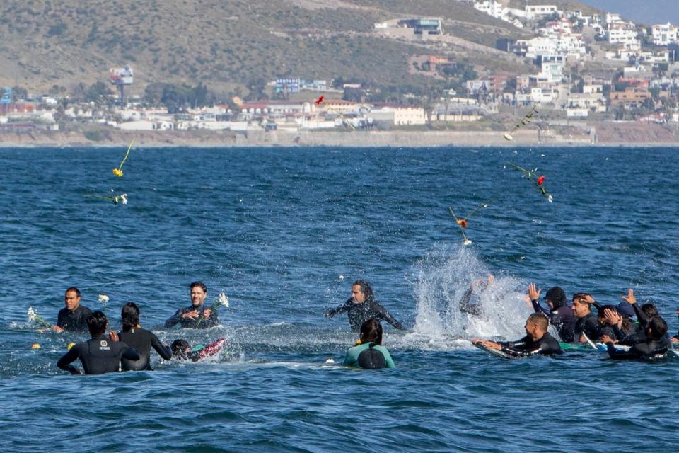 Surfistas lanzan flores durante un homenaje a remo a los tres surfistas fallecidos el domingo en Ensenada, México (AP)