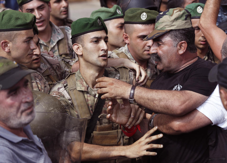 Lebanese army soldiers, left, push back their retired comrades, right, who are trying to enter the parliament building where lawmakers and ministers are discussing the draft 2019 state budget, in Beirut, Lebanon, Friday, July 19, 2019. The budget is aimed at averting a financial crisis in heavily indebted Lebanon. But it was met with criticism for failing to address structural problems. Instead, the budget mostly cuts public spending and raises taxes. (AP Photo/Hussein Malla)