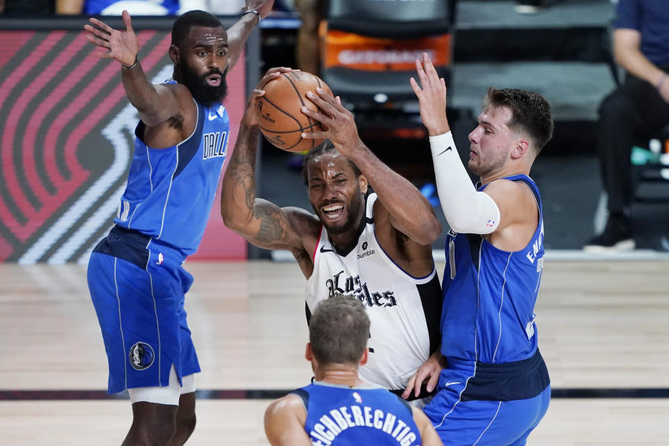 Los Angeles Clippers' Kawhi Leonard, center, is pressured by Dallas Mavericks' Luka Doncic, right, during the second half of an NBA basketball first round playoff game Friday, Aug. 21, 2020, in Lake Buena Vista, Fla. (AP Photo/Ashley Landis, Pool)