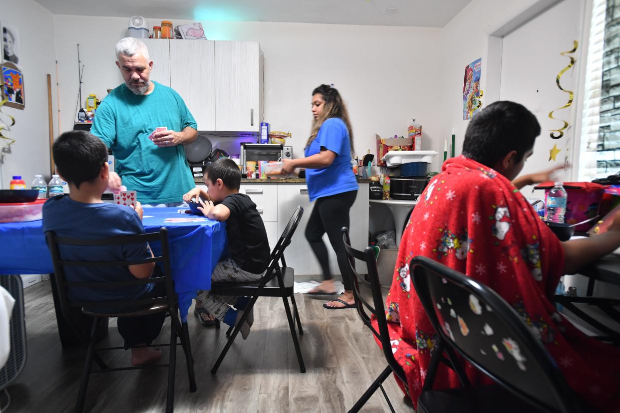 David Cabrera, center finishes a card game with his kids as his wife, Ria Singh begins serving a dinner of pork chops, beans and rice. The couple and their four children, Ian, 6, Kayla, 9, Dylan, 11 and Jaiden, 13, have been living in the Regency Inn on N. Tamiami Trail in Sarasota for two years.
