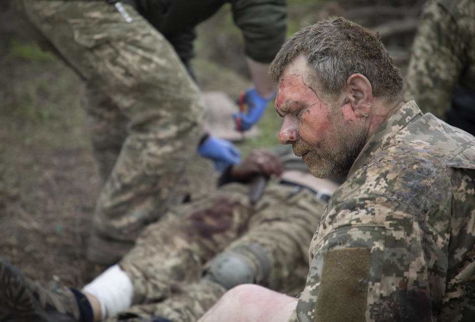 A soldier react as military medics give first aid to wounded soldiers on the road near Bakhmut, Donetsk region, Ukraine, Thursday, May 11, 2023. (AP Photo/Boghdan Kutiepov)