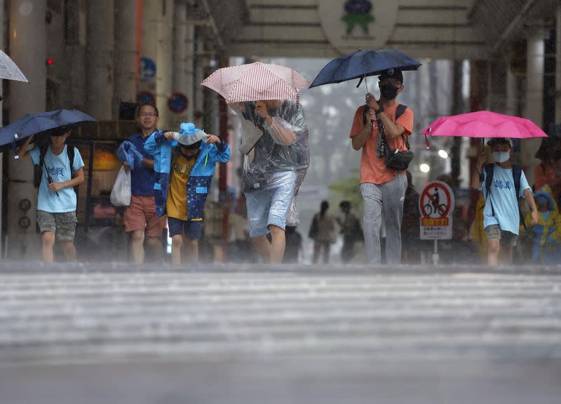 Passersby walk in a heavy rain and wind caused by Typhoon Khanun in Kagoshima, Japan