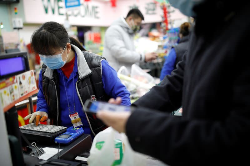 A cashier wearing a face mask works at a supermarket, as the country is hit by an outbreak of the new coronavirus, in Beijing