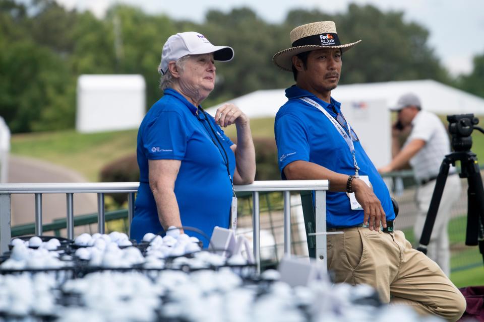 Volunteers Christine Dunn and Dandy Barawid talk while watching players practice their drives while standing next to the buckets of golf balls given out to players at the TPC Southwind driving range on Tuesday, August 9, 2022, two days before the start of the FedEx St. Jude Championship in Memphis, TN. Barawid, who has been volunteering for four years, said he comes back each year to see the golfers and because he enjoys helping and is a St. Jude contributor. Dunn, a lifelong Memphis resident, said she volunteers because, "It's a good cause and I enjoy being out in the fresh air, meeting people it's a lot of fun being out here."