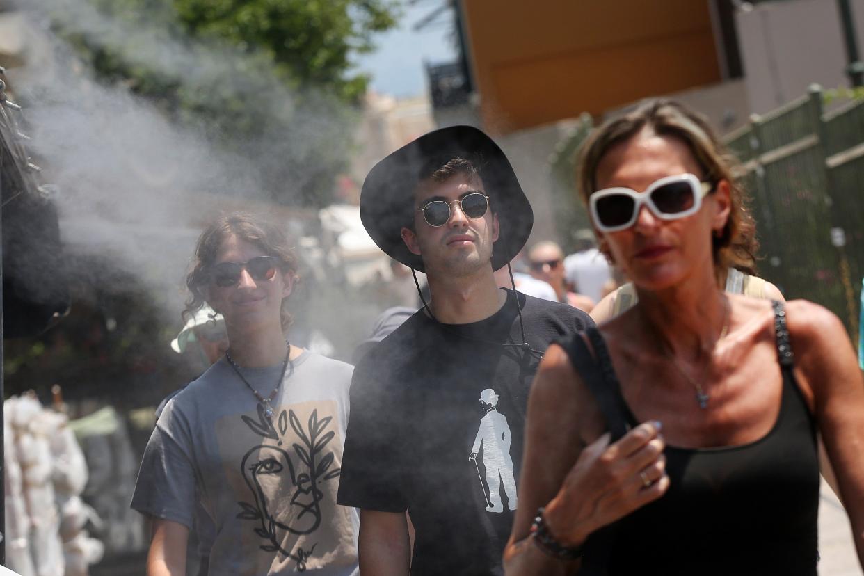 People cool off from a water spray device amid high temperatures in Athens, Greece (EPA)