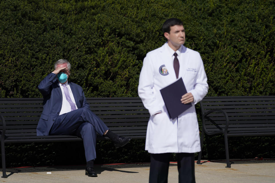 White House Chief of Staff Mark Meadows, seated left, and Dr. Sean Conley, physician to President Donald Trump, listen as doctors talk with reporters at Walter Reed National Military Medical Center, Monday, Oct. 5, 2020, in Bethesda, Md. (AP Photo/Evan Vucci)