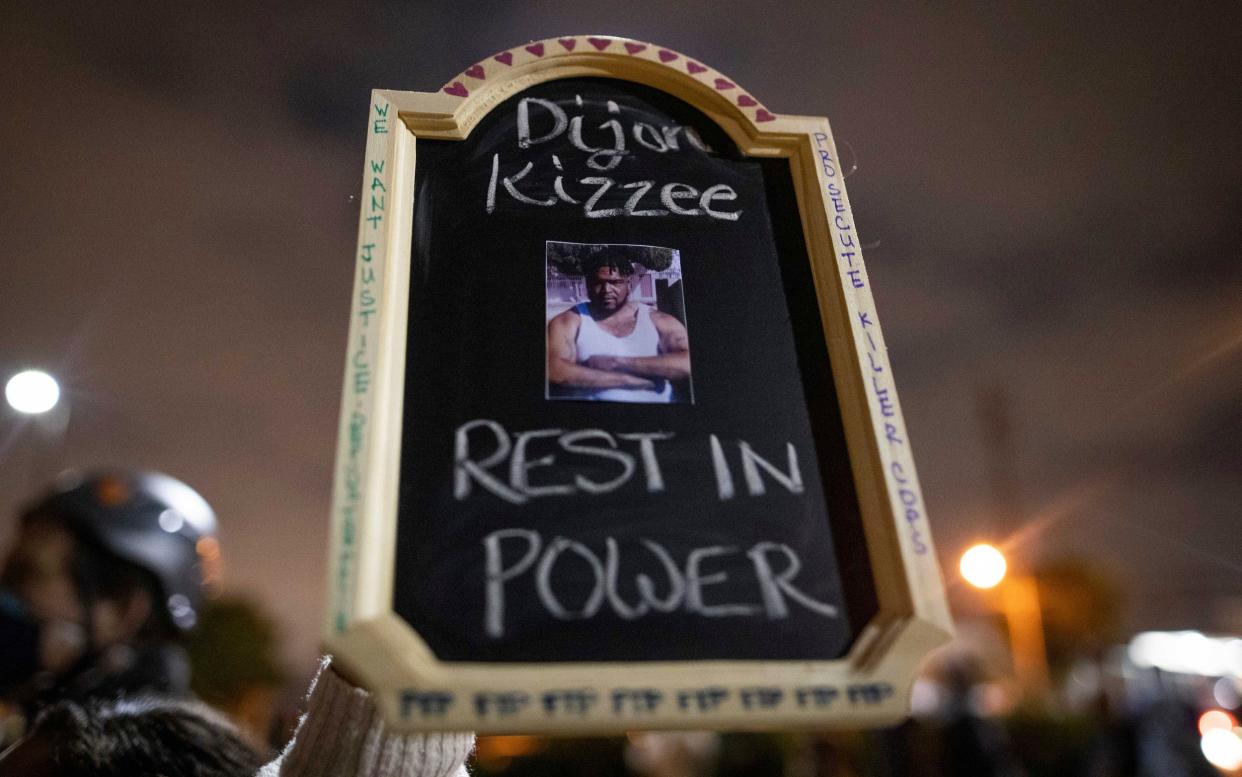 A protester holds a sign with a picture of Dijon Kizzee, who died after being shot by deputies of the Los Angeles Sheriff's Department on Monday - Christian Monterrosa/AP