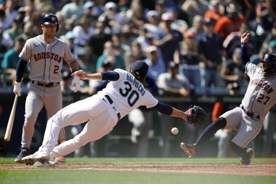 Houston Astros' Jose Altuve, right, slides in to score on a wild pitch as Seattle Mariners pitcher Ryan Borucki (30) attempts to tag him out during the eighth inning of a baseball game Saturday, July 23, 2022, in Seattle. (AP Photo/Ted S. Warren)