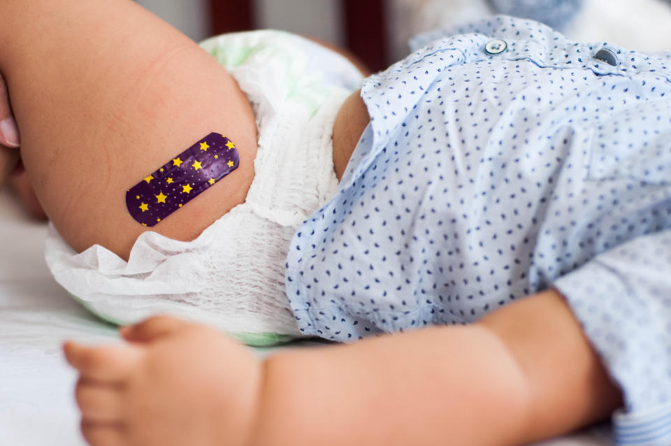 A close-up of a baby with a bandage on their leg, likely after getting vaccinated. (Photo via Getty Images)