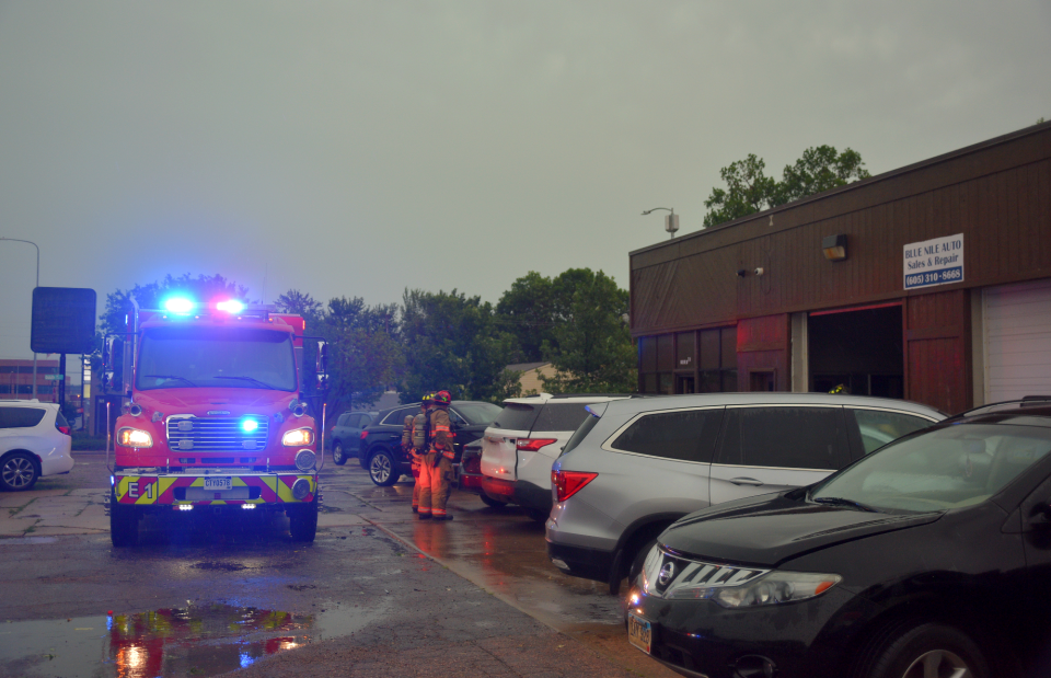 Firefighters monitor Blue Nile Auto for smoke after a downed power line started a fire on the roof of the shop garage Tuesday, July 5, 2022. Peak 80 mph wind gusts scattered tree debris throughout Sioux Falls, including a large branch behind the auto shop that started the fire.