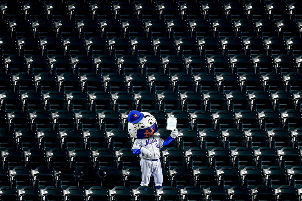 Mr. Met stands amongst empty seats with a sign reading "I found Nimmo" as Brandon Nimmo (not pictured) bats.