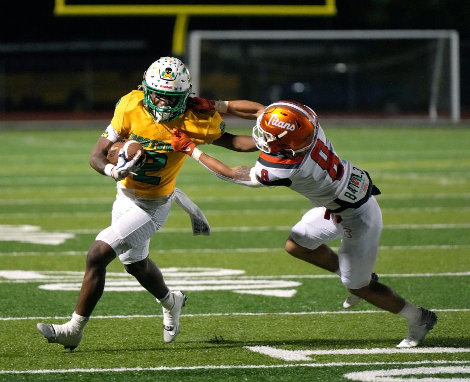 DeLand's Ladamion Bletcher (2) fights off an attempted tackle during a playoff game with University at New Smyrna Beach Sports Complex, Friday, Nov. 17, 2023.