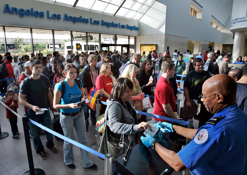 Travelers form a long security check line that is extended out of departure lounge at Los Angeles airport.