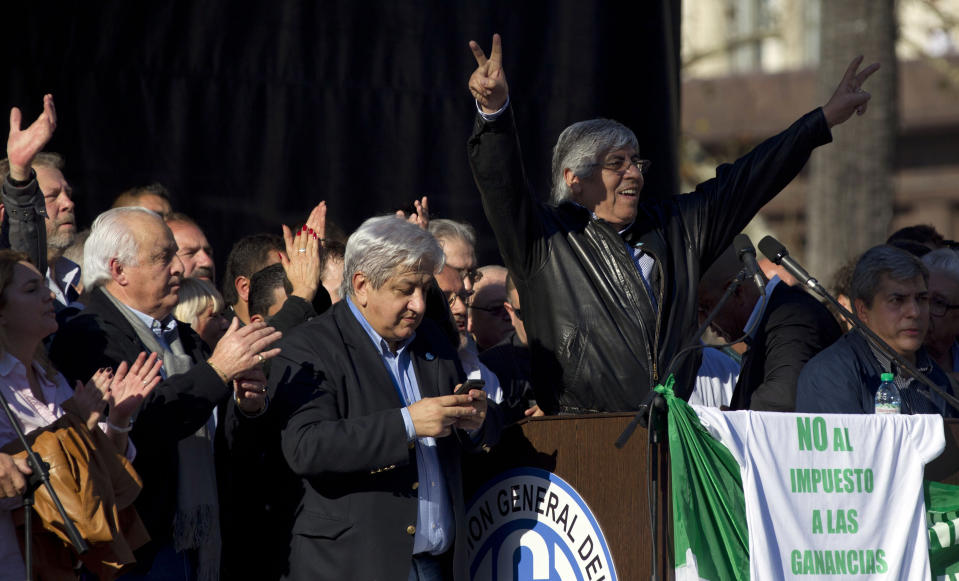 Union leader Hugo Moyano, right, gestures to protesters gathered at Plaza de Mayo in Buenos Aires, Argentina, Wednesday, June 27, 2012. A strike and demonstration called by union leader Moyano demands steps that would effectively reduce taxes on low-income people, among other measures. The sign reads in Spanish "No to taxes on profits." (AP Photo/Natacha Pisarenko)