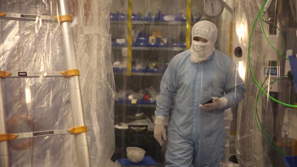 A lab worker wearing a full-body suit to avoid contaminating the dark matter detector works in the Sanford Underground Research Facility in Lead, S.D., on Dec. 8, 2019. Scientists have begun a new search for mysterious dark matter in a former gold mine a mile underground. Dark matter makes up the vast majority of the mass of the universe but scientists don't know what it is. (AP Photo/Stephen Groves)